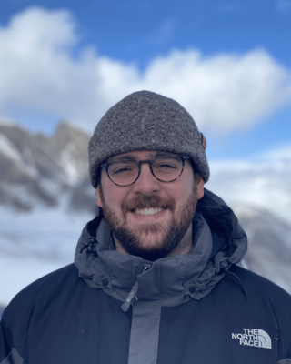 profile picture of Jonathan wearing a winter hat and glasses with mountains in the background